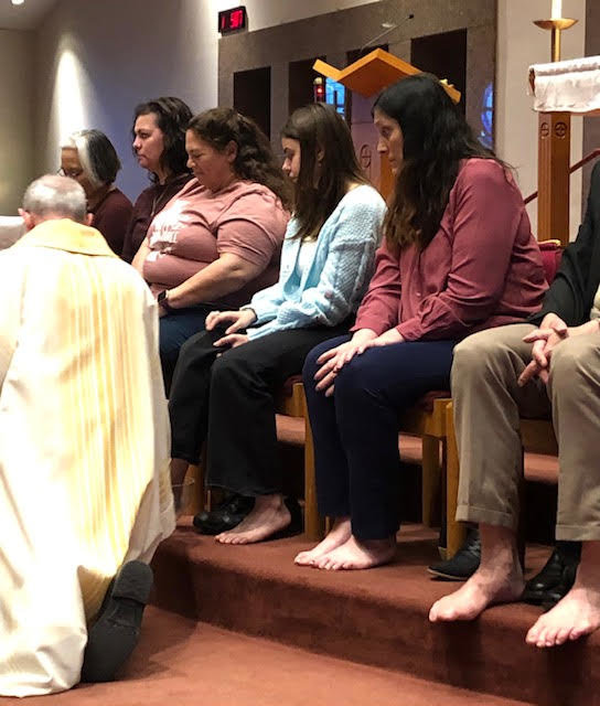Judith Giger (right) and Karolina (second from right), a foreign exchange student she is hosting in her home this year, who also served as her godmother through the Rite of Christian Initiation of Adults, await having their feet washed during the Mass of the Lord’s Supper on Holy Thursday, April 14, in Our Lady of Lourdes Church in Columbia.